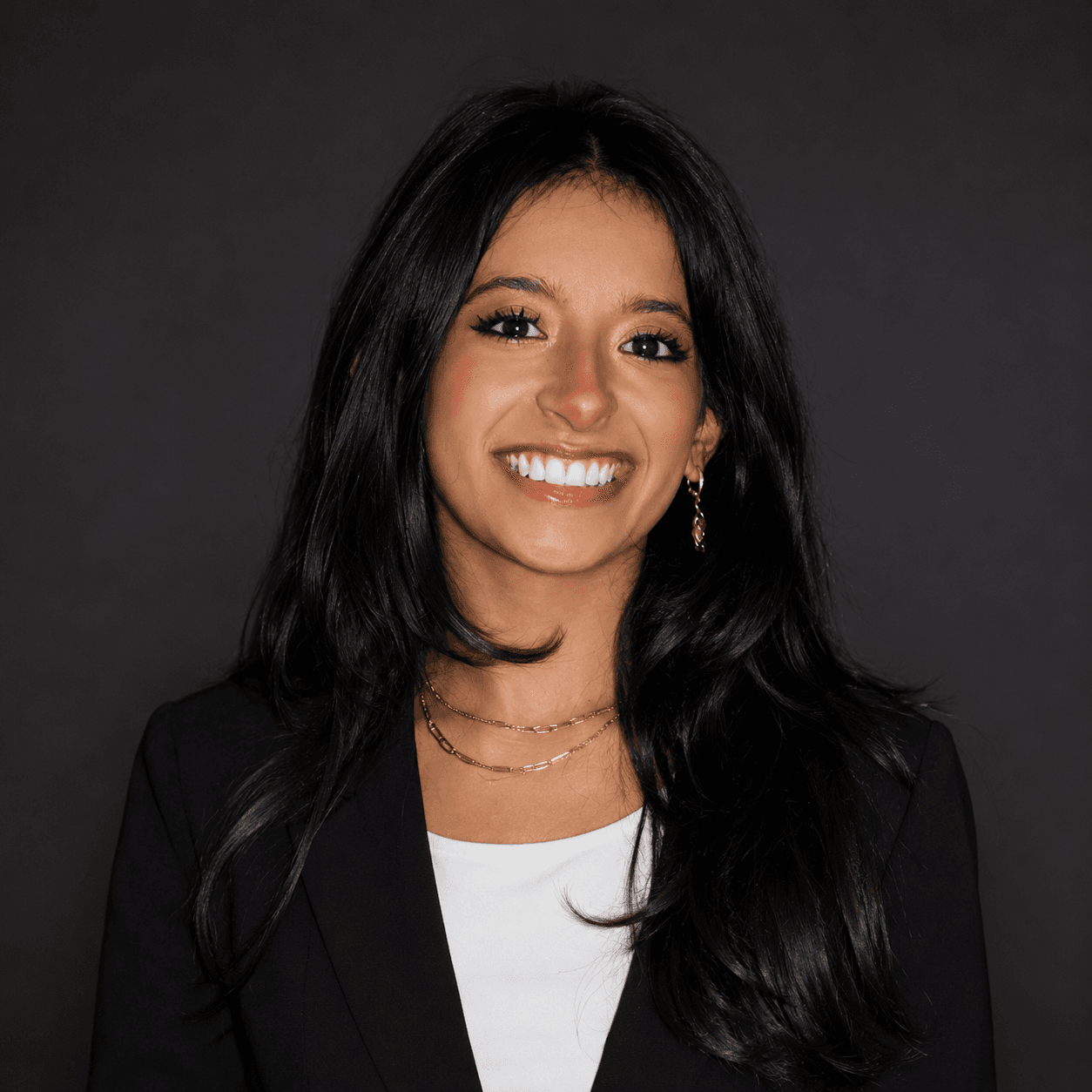 Portrait of Nimita Mishra smiling against a dark background.
